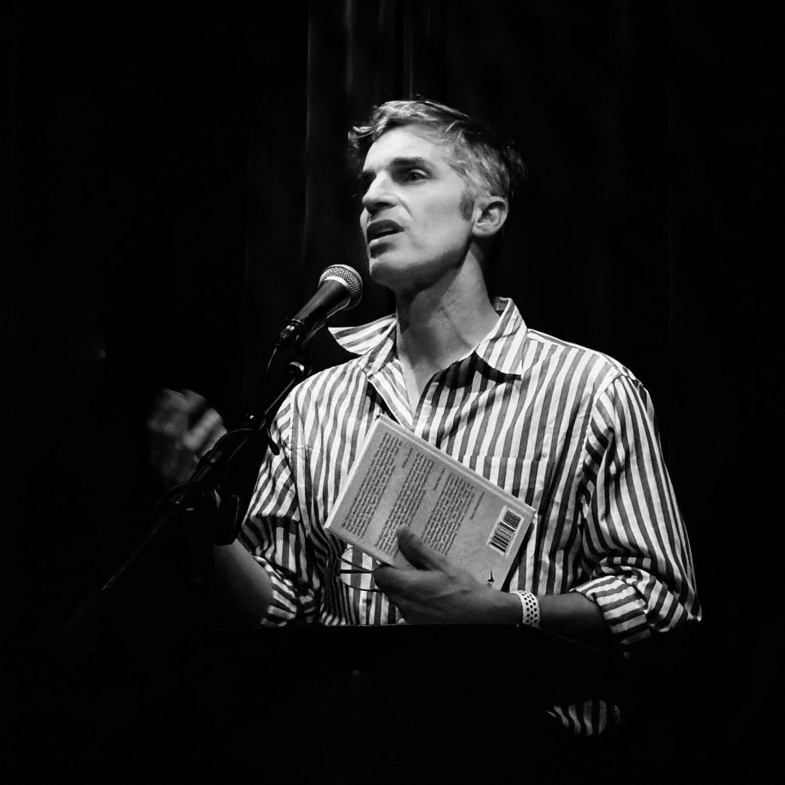 Blas Falconer reading at the microphone, book in hand